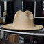 Beige straw hat on a black surface with a blurred background