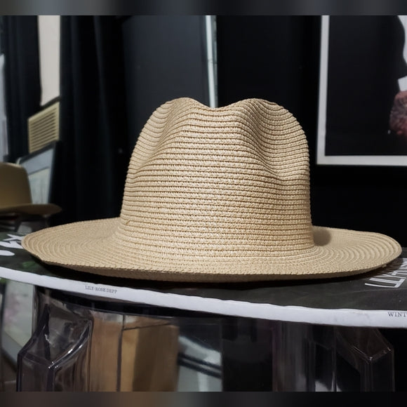 Beige straw hat on a black surface with a blurred background