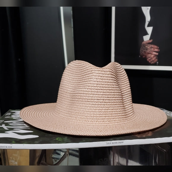 Beige straw hat on a black surface with a blurred background