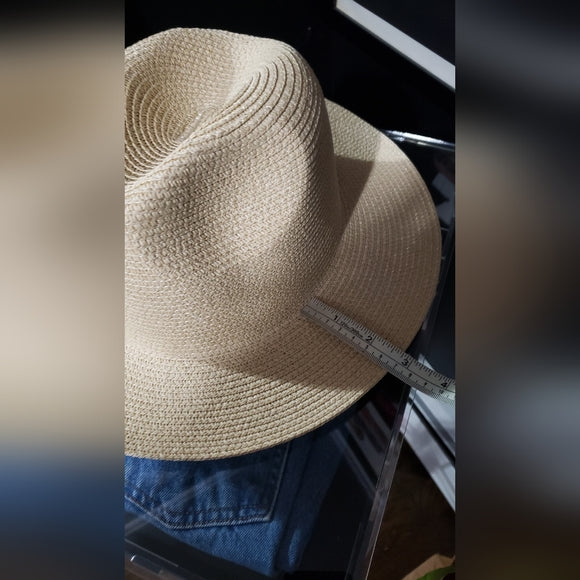 Beige straw hat on a mannequin with a measuring tape, against a blurred background.