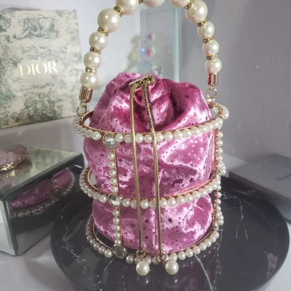 Pink glittery handbag with pearl handle on a dark surface